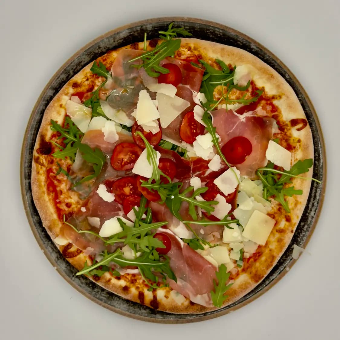 Pizza mit Parmaschinken, Rucola und Grana