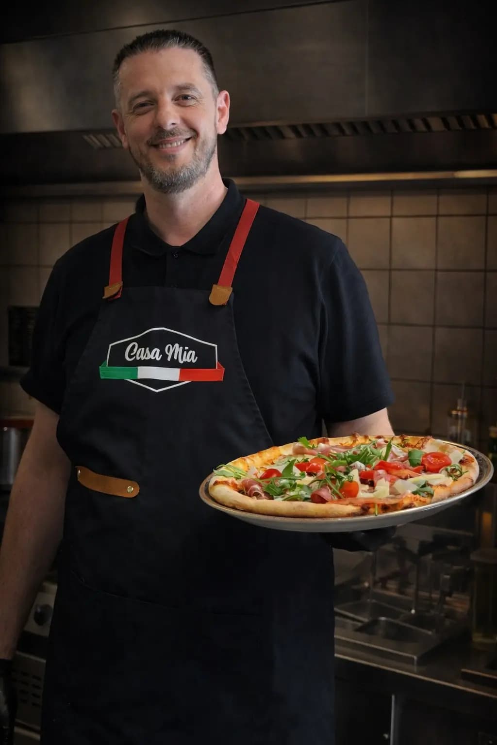 Unser Pizzaiolo mit einer frisch gebackenen Pizza